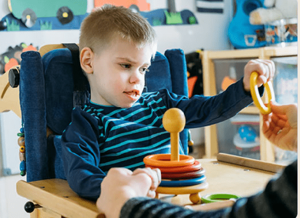 cerebral palsy and hearing loss.<br />
A child with cerebral palsy uses a walker while laughing in a playground.<br />
